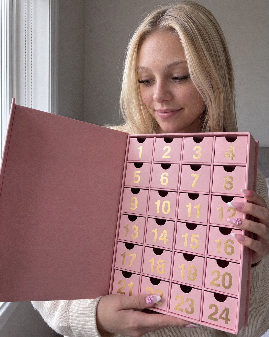 Lily regarde les tiroirs du calendrier de l'Avent ouvert, un léger sourire aux lèvres.